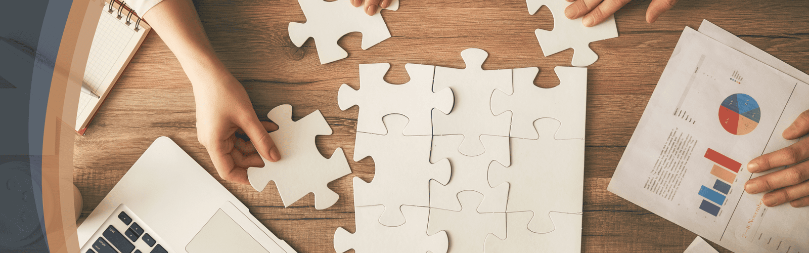 Tabletop view of hands collaborating around laptop and financial charts with puzzle pieces in Optimum Transitions colors, representing ESOP services, exit planning, growth and M&A strategies, and financial advisory support